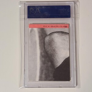 May include: A graded trading card featuring a black and white image of a person's head and shoulders. The card is in a protective plastic case with a red label that reads "#269 C's GRANING".