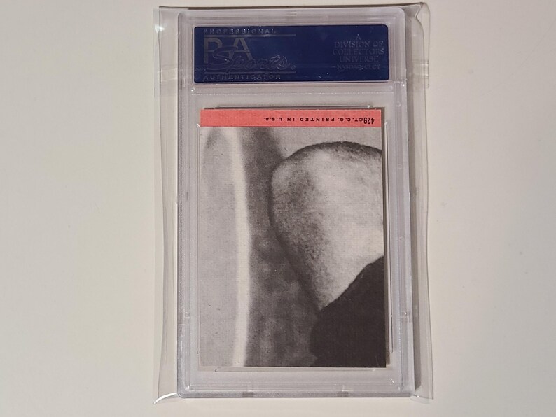 May include: A graded trading card featuring a black and white image of a person's head and shoulders. The card is in a protective plastic case with a red label that reads "#269 C's GRANING".