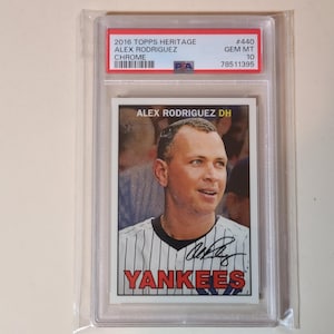 May include: A baseball card featuring Alex Rodriguez in a New York Yankees uniform. The card is encased in a protective holder and includes the text "2016 Topps Heritage" and "Yankees". The card is graded as GEM MT 10.