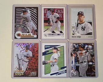 May include: Six individual trading cards featuring Aaron Judge of the New York Yankees in various poses, including batting and fielding. Each card is encased in a clear protective plastic sleeve, displaying the player in his pinstriped uniform.