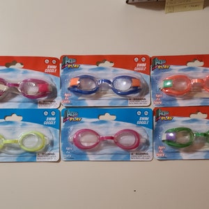 May include: Six packages of Aqua Play swim goggles for kids. Each package features a different color combination of goggles, including pink, blue, orange, green, yellow, and purple. The packages are labeled with the brand name, product name, and age recommendation.