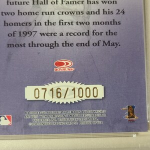 May include: A purple and gold baseball card with a picture of a baseball player. The card has the text "Donruss" and "0716/1000" on it. The card also has the text "Major League Baseball trademarks and copyrights are used with permission of Major League Baseball Properties, Inc. Official Licensee of MLBPA. &copy;1998 Donruss Trading Card Co. Product of USA."