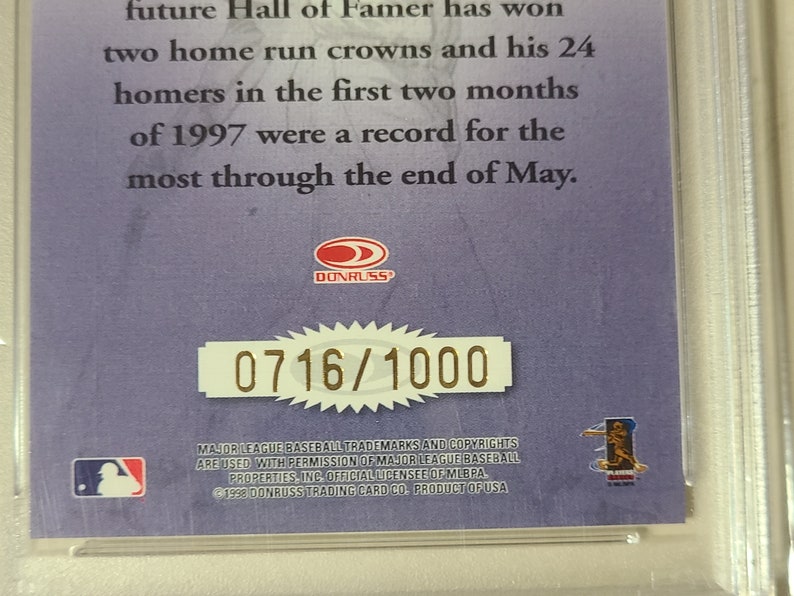 May include: A purple and gold baseball card with a picture of a baseball player. The card has the text "Donruss" and "0716/1000" on it. The card also has the text "Major League Baseball trademarks and copyrights are used with permission of Major League Baseball Properties, Inc. Official Licensee of MLBPA. &copy;1998 Donruss Trading Card Co. Product of USA."