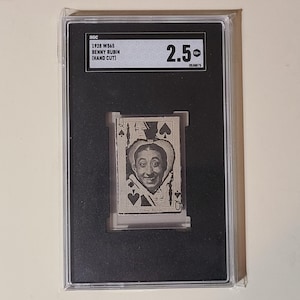 May include: A black and white photo of Benny Rubin, a comedian, in a card-themed image. The card is a Queen of Spades. The image is in a black frame with a white label that reads "1928 WS45 Benny Rubin (Hand Cut)" and "2.50".