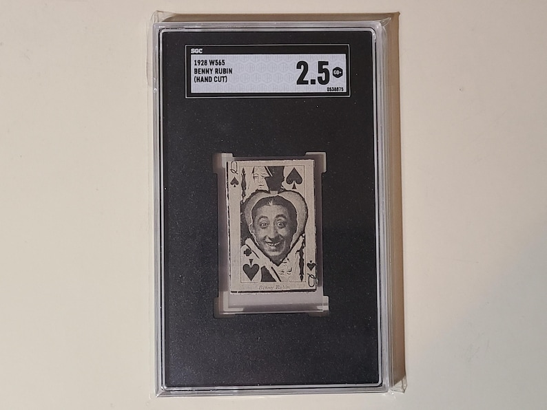 May include: A black and white photo of Benny Rubin, a comedian, in a card-themed image. The card is a Queen of Spades. The image is in a black frame with a white label that reads "1928 WS45 Benny Rubin (Hand Cut)" and "2.50".