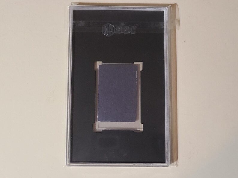 May include: A black plastic case with a clear plastic front, displaying a dark blue card with the word "PSA" in white lettering.