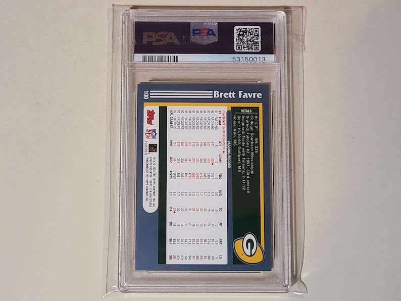 May include: A Brett Favre football card, encased in a protective plastic holder. The card's back features player statistics, team logos, and the text "Brett Favre". The card is graded and authenticated by PSA.