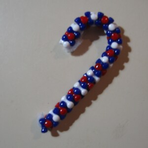 May include: A red, white, and blue candy cane ornament made of beads.