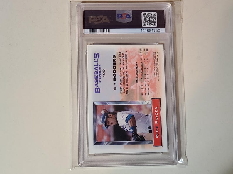 May include: A baseball card in a clear plastic case. The card shows Mike Piazza in a Dodgers uniform. The card is labelled "Baseball's Finest" and "199". The case has a PSA label and a serial number.