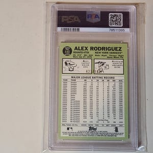 May include: A baseball card of Alex Rodriguez, graded and encased by PSA. The card features a photo of Rodriguez and his stats, including his height of 6'3" and weight of 225 lbs. The card is from the Topps series.