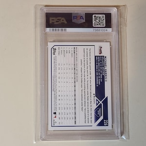 May include: A baseball card of Michael Harris II, Atlanta Braves, graded by PSA. The card is encased in a clear plastic holder with the PSA logo and a QR code. The card's back features player stats and a brief biography.