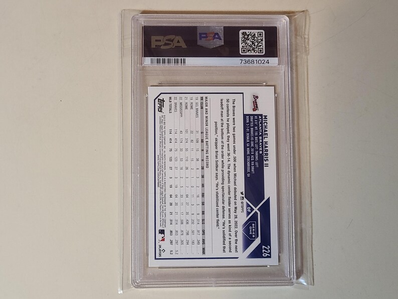 May include: A baseball card of Michael Harris II, Atlanta Braves, graded by PSA. The card is encased in a clear plastic holder with the PSA logo and a QR code. The card's back features player stats and a brief biography.