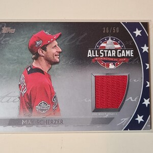 May include: A Topps baseball trading card featuring Max Scherzer in a red jersey and cap. The card displays the 2018 All-Star Game Washington DC logo, a red fabric swatch of event-worn memorabilia, and the serial number 36/50 printed in white.