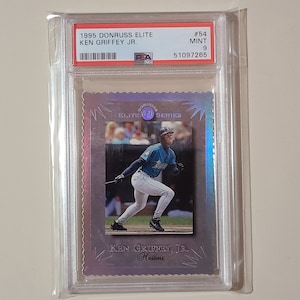 May include: A 1995 Donruss Elite Series baseball card featuring Ken Griffey Jr. of the Mariners. The card is graded 9 by PSA and has a holographic finish.