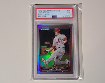 May include: A 2012 Bowman Chrome Mike Trout baseball card, refractor, graded 9, with a red, white, and blue color scheme. The card features a photo of Mike Trout in his Angels uniform, sliding into home plate.