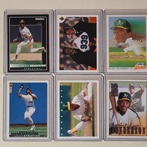 May include: A collection of nine baseball trading cards featuring a baseball player, Ricky Henderson, in various poses. The cards are in protective plastic sleeves and feature different card manufacturers, including Pinnacle, Upper Deck, and Score.