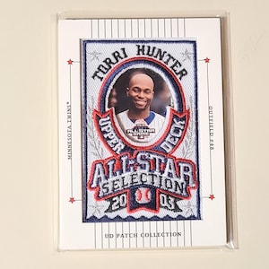 May include: A baseball card featuring Torii Hunter of the Minnesota Twins. The card has a patch with the text "ALL-STAR SELECTION 2003" and "UPPER DECK". The card is in a protective sleeve.