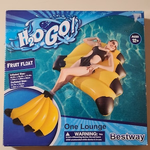 May include: A yellow and black inflatable banana pool float with a woman laying on it. The box reads "H₂O GO! Fruit Float One Lounge" and "Bestway".