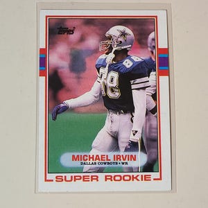 May include: A Topps football trading card featuring Michael Irvin of the Dallas Cowboys. The card has a red border with blue and purple accents. Irvin is wearing a white and blue uniform with the number 88.