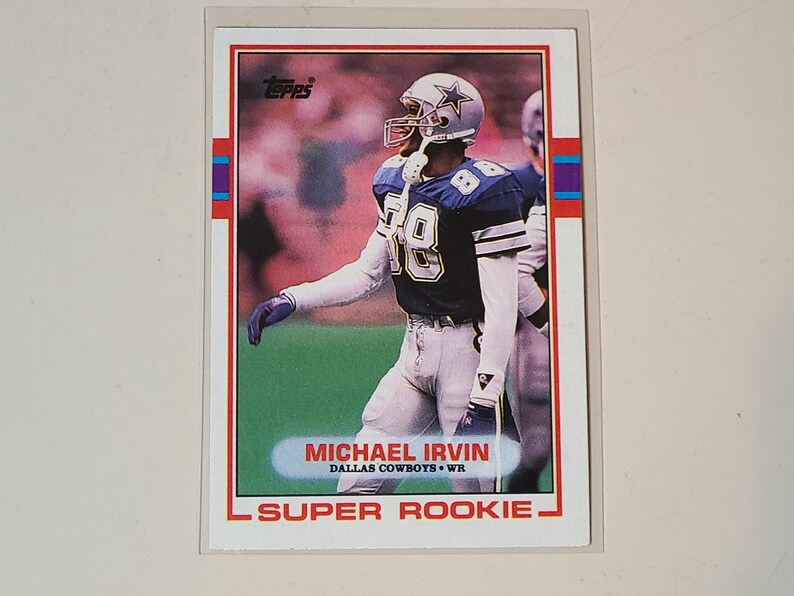 May include: A Topps football trading card featuring Michael Irvin of the Dallas Cowboys. The card has a red border with blue and purple accents. Irvin is wearing a white and blue uniform with the number 88.