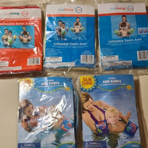 May include: Four packages of inflatable swim arm bands for kids. The packages are all different colors and have different designs. The packages are all labeled with the brand name "trueliving" and the words "Inflatable Swim Arm".