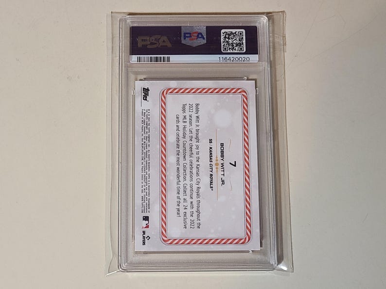 Op de afbeelding: Een honkbalkaart in een doorzichtige plastic hoes. De kaart toont "BOBBY WITT JR." en "SS KANSAS CITY ROYALS." De kaart is beoordeeld door PSA, met een zichtbaar serienummer. De kaart heeft een rood-witte rand.