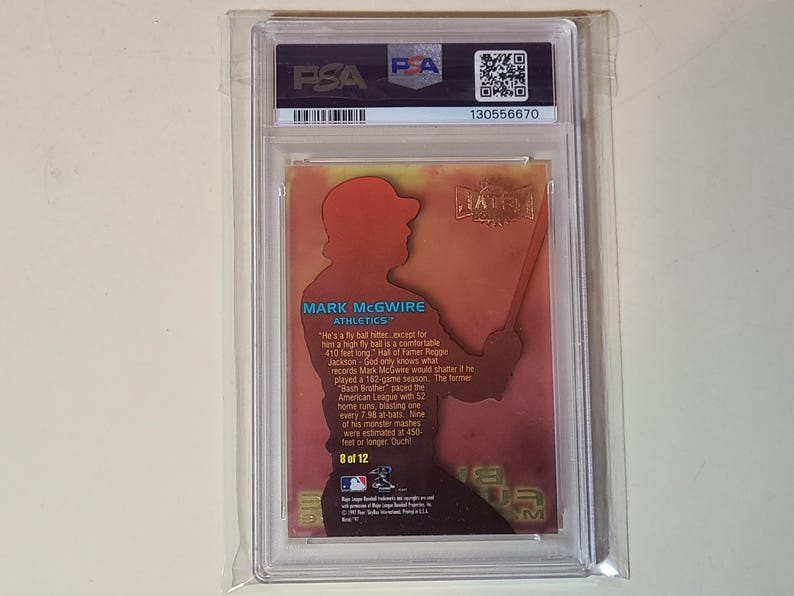 May include: A baseball card encased in a protective holder. The card features a silhouette of a baseball player in a batting stance, with the name "MARK MCGWIRE" and the Athletics team logo. The card is graded by PSA.