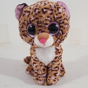 May include: A brown and tan plush leopard with large, glittery eyes. The leopard has pink accents on its nose and ears.