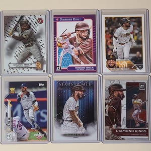 May include: A collection of nine baseball trading cards featuring Fernando Tatis Jr. of the San Diego Padres. The cards are from different sets, including Diamond Kings, Stars of MLB, and Opening Day. The cards feature different photos of Tatis Jr. in action, as well as his name and team logo.
