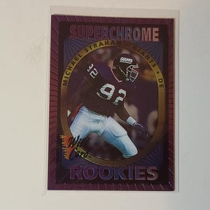 May include: A SuperChrome rookie card featuring Michael Strahan of the New York Giants. The card has a purple and gold border with the words "SuperChrome" and "Rookies" at the top and bottom. Strahan is in his Giants uniform.