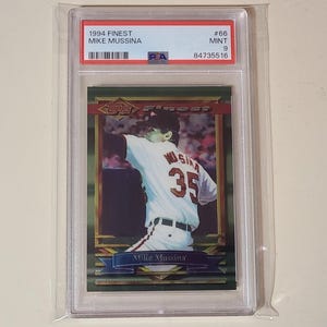 Puede incluir: Una tarjeta de b&eacute;isbol Mike Mussina de 1994 Topps Finest, calificada como Mint 9 por PSA. La tarjeta muestra a un jugador con uniforme blanco y el n&uacute;mero 35 en la espalda, encapsulada en un estuche de pl&aacute;stico transparente con etiqueta blanca.