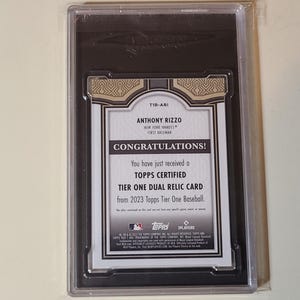 May include: A Topps Certified Tier One Dual Relic Card from 2023 Topps Tier One Baseball. The card features Anthony Rizzo, a first baseman for the New York Yankees. The card is in a protective case.