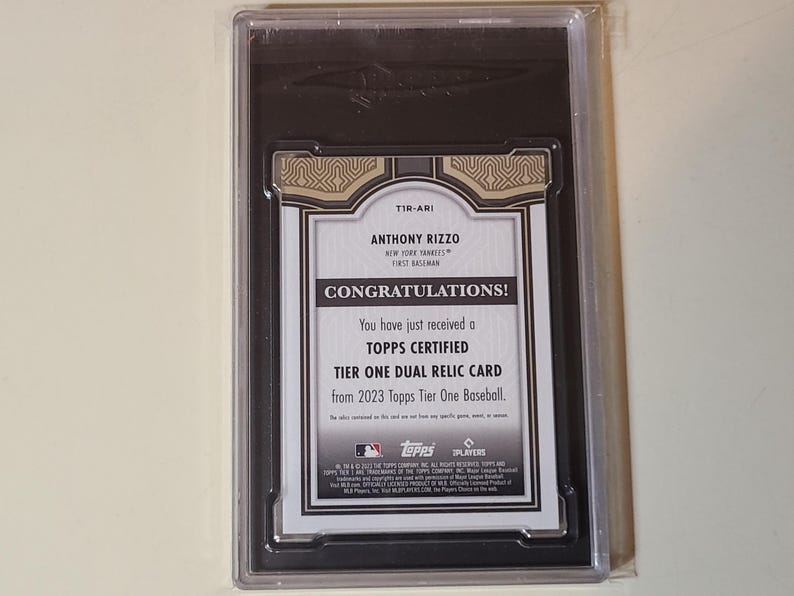 May include: A Topps Certified Tier One Dual Relic Card from 2023 Topps Tier One Baseball. The card features Anthony Rizzo, a first baseman for the New York Yankees. The card is in a protective case.