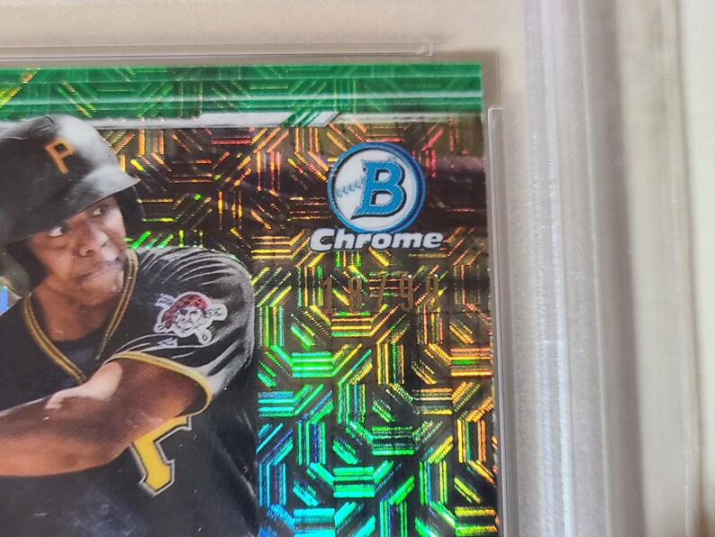 Puede incluir: Una tarjeta de b&eacute;isbol con un jugador con el uniforme de los Piratas de Pittsburgh. La tarjeta tiene un fondo hologr&aacute;fico verde y dorado con la palabra "Chrome" y el logotipo de Bowman. El jugador lleva un casco negro.