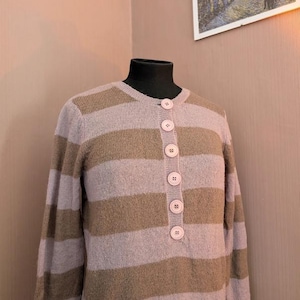 May include: A striped sweater with long sleeves and a button-up front. The sweater is brown and light pink with a horizontal stripe pattern.