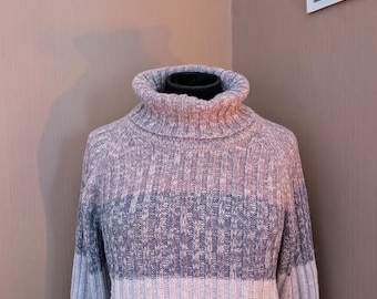 May include: A striped turtleneck sweater in shades of gray, white, and brown. The sweater is made of a soft, knitted fabric.