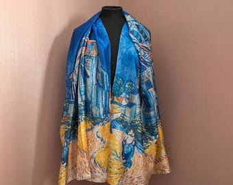 Puede incluir: Una bufanda de seda azul con una pintura de una ciudad y un campo amarillo. La pintura recuerda el estilo de Vincent van Gogh.
