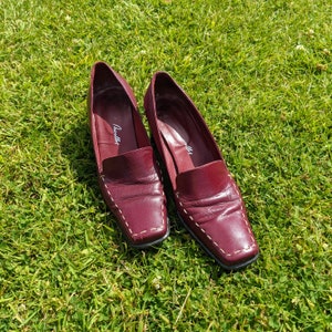 May include: A pair of burgundy leather loafers with white stitching. The loafers have a square toe and a low heel. The brand name "Giulietta" is visible on the inside of each shoe.