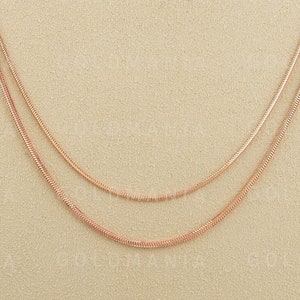 May include: Three gold chains of different lengths and widths, layered on a beige mannequin bust.