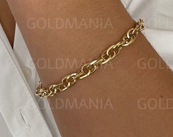 Puede incluir: Un brazalete de cadena de oro con un diseño de eslabones de curb. El brazalete se lleva en la muñeca.