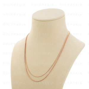May include: A rose gold chain necklace on a white mannequin. The necklace is made of two thin chains, one slightly thicker than the other.