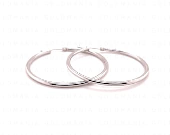 May include: A pair of silver hoop earrings. The earrings are round with a smooth, polished finish. The hoops are a classic design, suitable for everyday wear. The earrings are displayed against a white background.