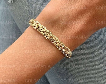 May include: A gold chain bracelet with a woven design. The bracelet is on a person's wrist.
