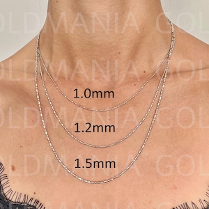 Three 14k solid white gold bar and bead chains of different thicknesses, 1.0mm, 1.2mm, and 1.5mm, layered on a woman's neck. Comes with lobster clasp