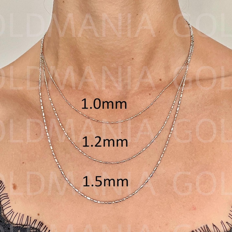 Three 14k solid white gold bar and bead chains of different thicknesses, 1.0mm, 1.2mm, and 1.5mm, layered on a woman's neck. Comes with lobster clasp