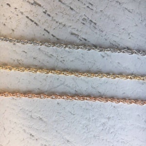 May include: Three chains of different metals: silver, gold, and rose gold. The chains are all the same style, with a delicate, twisted design.