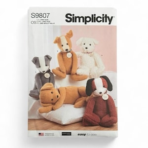 May include: A Simplicity S9807 sewing pattern envelope featuring illustrations of four plush dogs in various colors including grey, tan, white, and reddish-brown. Each dog has a small circular tag around its neck. The text includes Simplicity, S9807, and easy-to-sew.