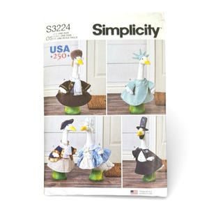 May include: Simplicity sewing pattern S3224 featuring instructions for five different outfits for a decorative goose figurine. The outfits include a brown coat with a fur hat, a light blue Statue of Liberty costume, a colonial style outfit, a blue dress, and a tuxedo.