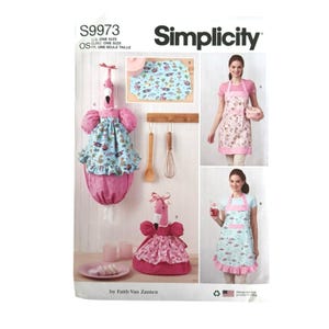 May include: Simplicity S9973 sewing pattern envelope featuring instructions for kitchen accessories. The design includes flamingo-shaped plastic bag holders, a patterned fabric mat, and two styles of aprons with ruffled hems and flamingo prints.