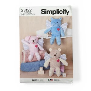 May include: Simplicity S3122 sewing pattern envelope featuring three plush angel toys: a pink rabbit, a blue cat, and a tan bear. Each stuffed animal has white wings and a red heart appliqué on its chest. The text includes Simplicity, S3122, and easy-to-sew.